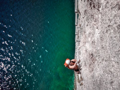 男子攀岩附近水体 · 免费素材图片