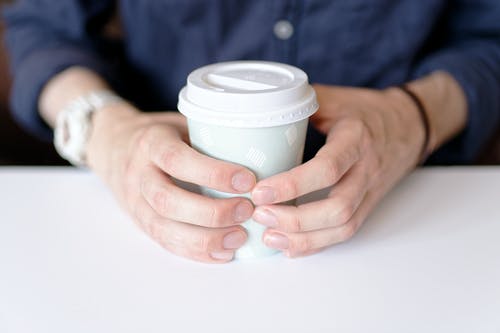 拿着白皮书杯的人的照片 · 免费素材图片