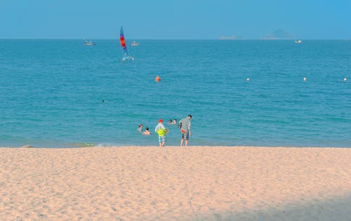 两个孩子站在海边，在蓝蓝的天空下 · 免费素材图片