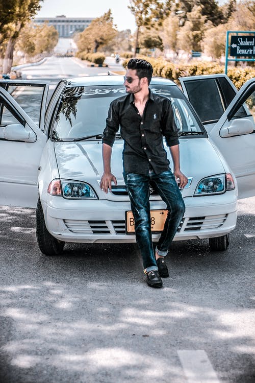 坐在白色汽车引擎盖上的男人 · 免费素材图片