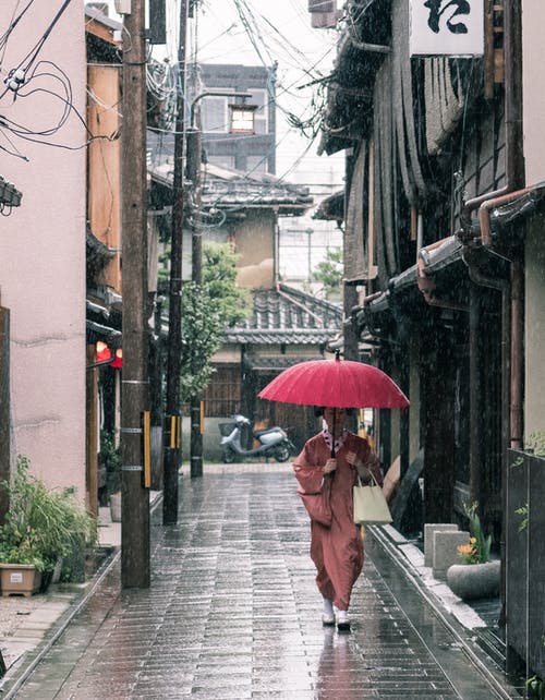 棕色的长袍，拿着伞走在混凝土通路上的女人 · 免费素材图片