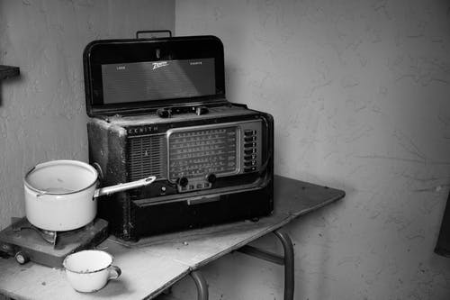 老式收音机在炉灶旁的炉灶的灰度照片 · 免费素材图片