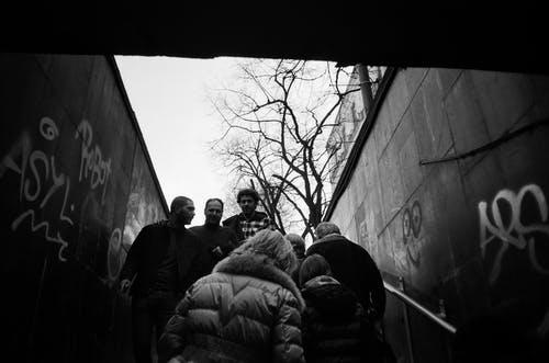 在混凝土墙之间行走的人的灰度照片 · 免费素材图片