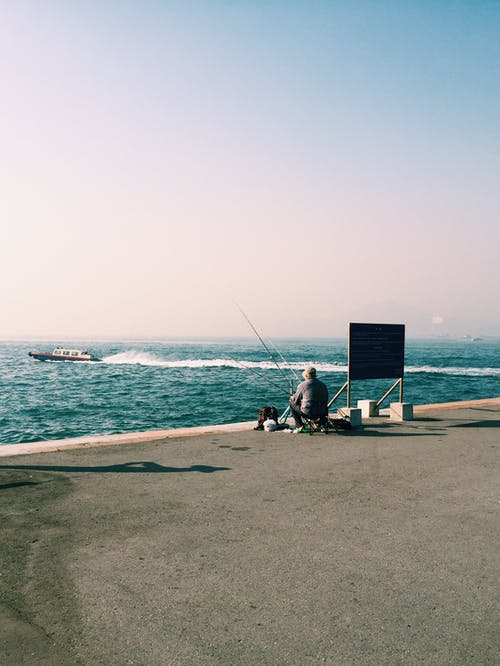男子坐在海边 · 免费素材图片