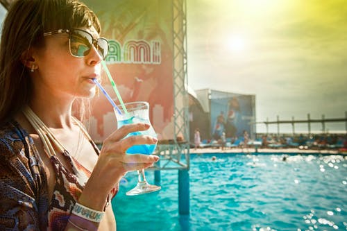 女人在地下游泳池旁压缩蓝色饮料 · 免费素材图片