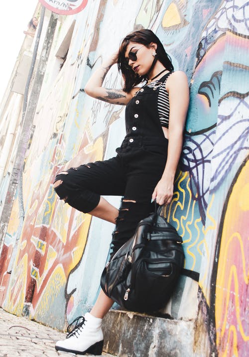 女人靠在墙上时，按住背包 · 免费素材图片