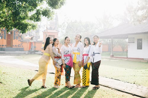 六名妇女站在橙色大楼附近拍照 · 免费素材图片