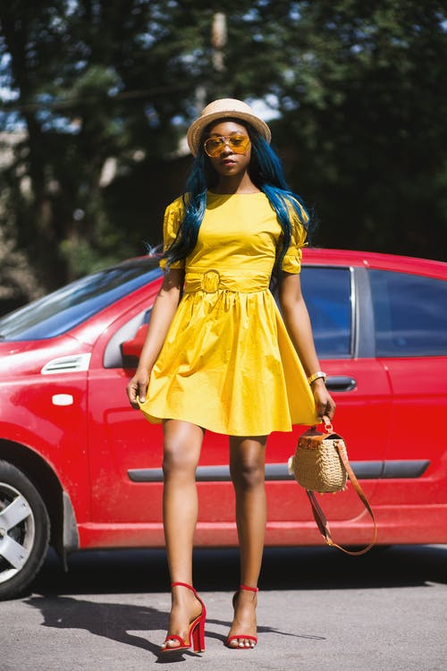 穿黄色船领短袖礼服站在红色汽车附近的女人 · 免费素材图片