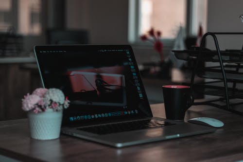 Macbook在浅焦点摄影杯旁边的桌子上 · 免费素材图片