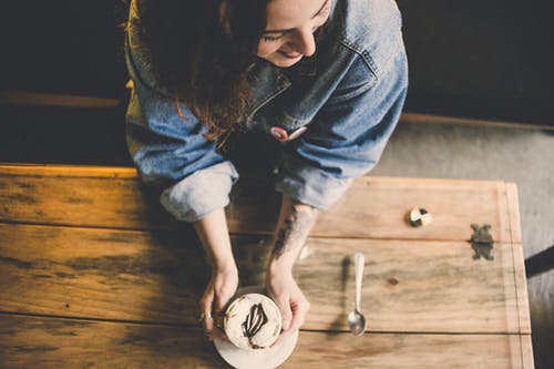 女人抱着蛋糕站在桌子旁边 · 免费素材图片