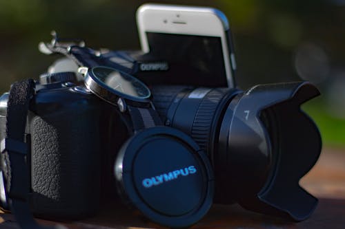 银色iphone 6旁的黑色olympus Dslr相机 · 免费素材图片
