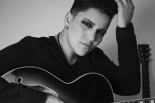 女人抱着吉他的灰度照片 · 免费素材图片