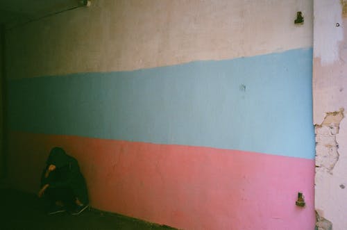 倚在蓝色，白色和粉红色的墙上的人 · 免费素材图片