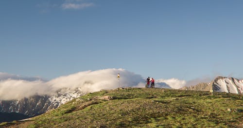 两个男人站在白雪覆盖的山附近的山上 · 免费素材图片