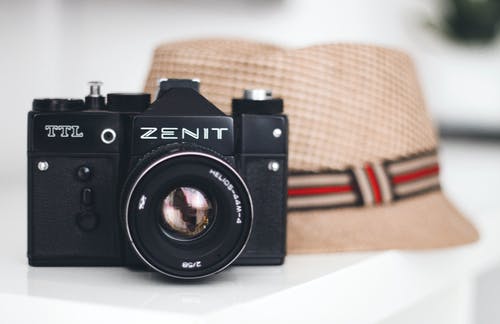 Zenit品牌相机在fedora帽子旁边 · 免费素材图片