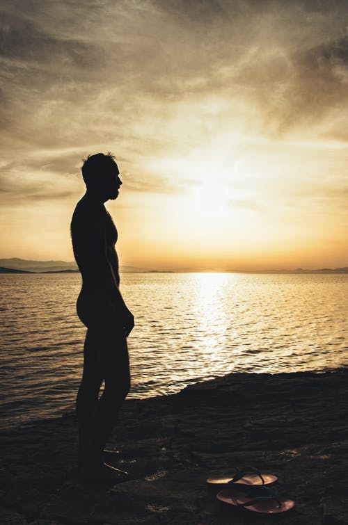 日落期间水体附近的沙滩上的裸照人 · 免费素材图片