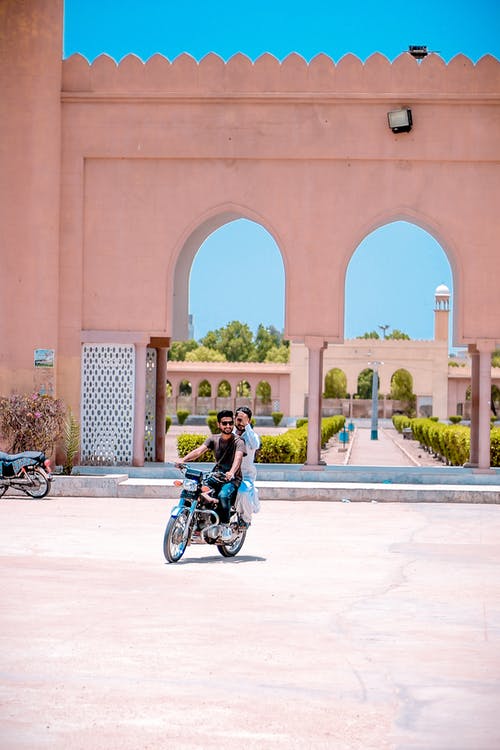 两人骑摩托车在混凝土建筑附近 · 免费素材图片