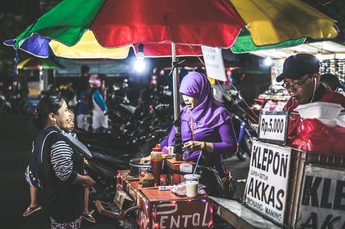 女人穿着紫色盖头卖食物 · 免费素材图片
