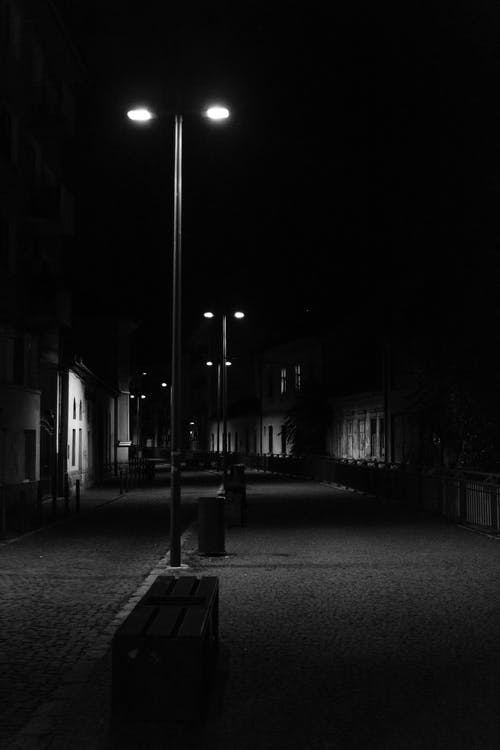 房屋之间道路上的路灯的灰度摄影 · 免费素材图片