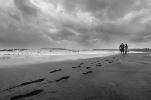 夫妻在海边散步的灰度照片 · 免费素材图片