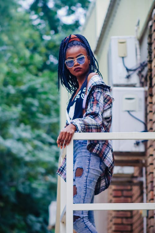 女人站在栏杆旁，站在白色的室外交流单元附近 · 免费素材图片