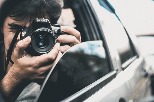 拍摄照片时，男子手持佳能相机在车内 · 免费素材图片