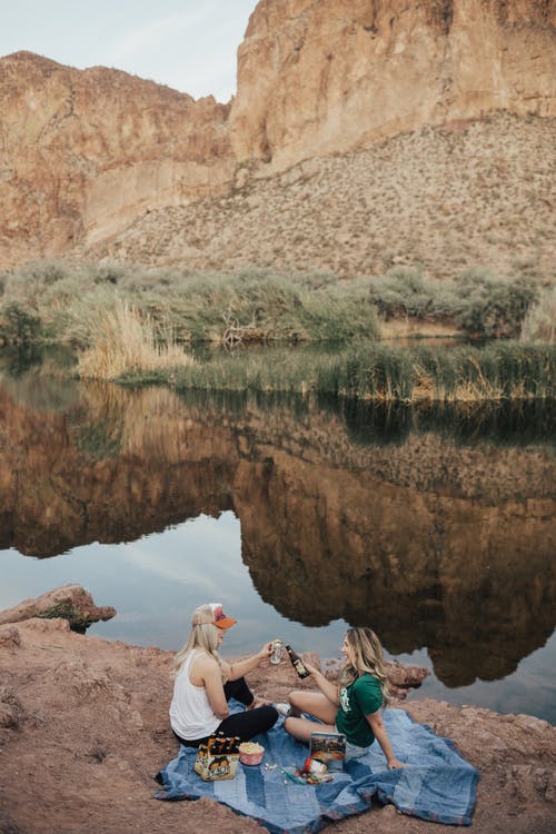 两个女人坐在水体附近 · 免费素材图片