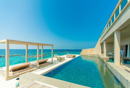 灰色花岗岩游泳池和海滩旁室外休息室的建筑摄影 · 免费素材图片