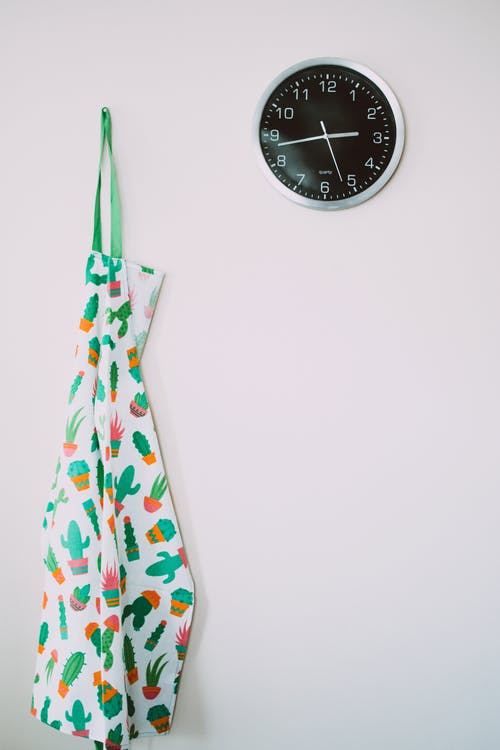 圆形灰色模拟壁钟附近的白色和绿色仙人掌图案围裙 · 免费素材图片