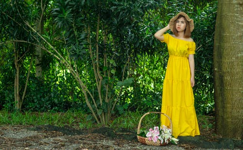 女人在花篮旁边穿黄色的连衣裙 · 免费素材图片