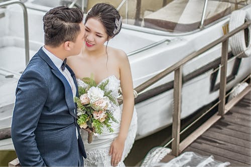 新婚夫妇站在船附近的棕色木码头上 · 免费素材图片