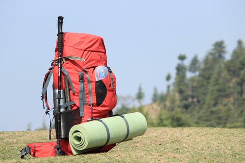 红色远足在绿草的背包的选择聚焦照片 · 免费素材图片