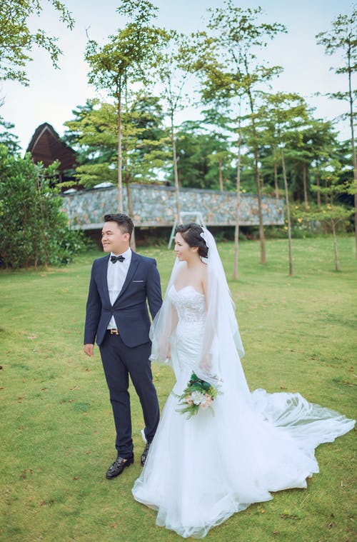 夫妇身穿婚纱，穿着灰色建筑附近的礼服 · 免费素材图片