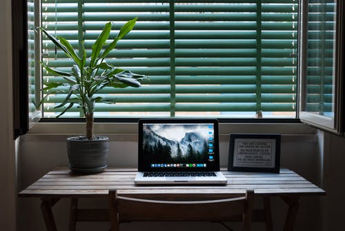 Macbook Air的照片在桌上的房子植物和相框旁边。 · 免费素材图片