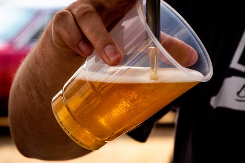 人把啤酒倒在透明杯上 · 免费素材图片