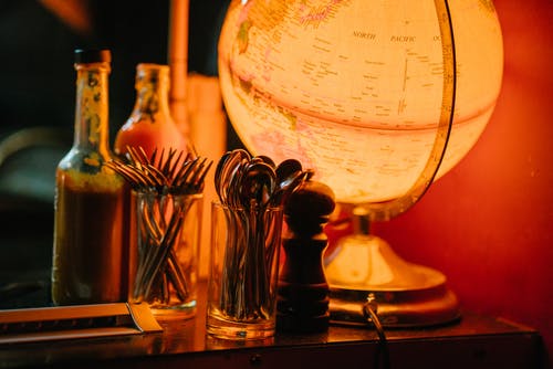 调料罐和餐具套装旁边的带灯的书桌地球仪 · 免费素材图片