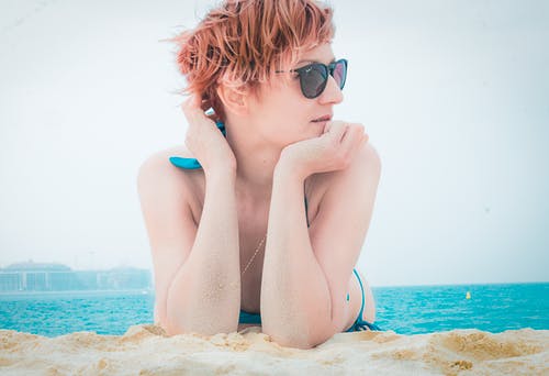 躺在靠近水体的棕色沙滩上的女人 · 免费素材图片