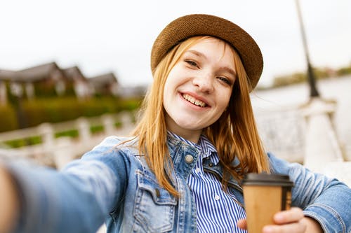 妇女的选择聚焦照片微笑时拿着咖啡杯的蓝色牛仔布夹克的 · 免费素材图片
