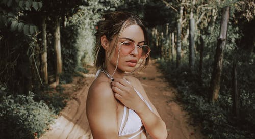 森林之间穿白色胸罩和金色框架太阳镜的女人 · 免费素材图片
