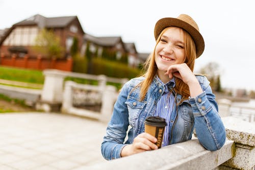 女人抱着杯茶，靠在栅栏上 · 免费素材图片