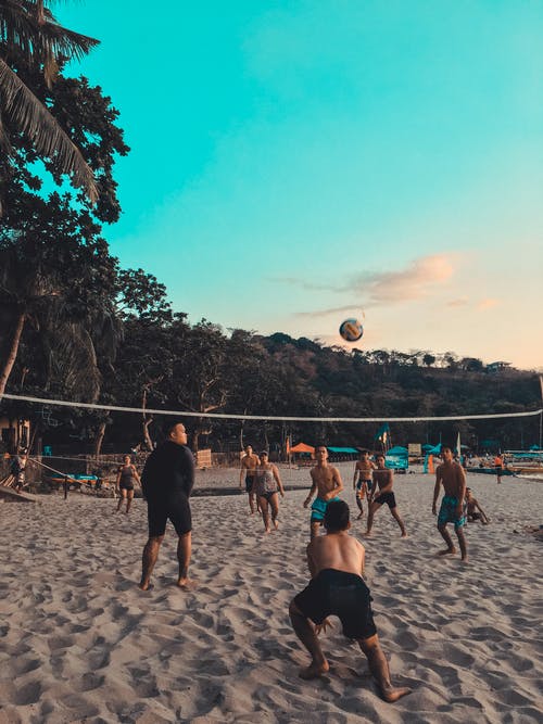 一群人在沙滩上打沙滩排球 · 免费素材图片
