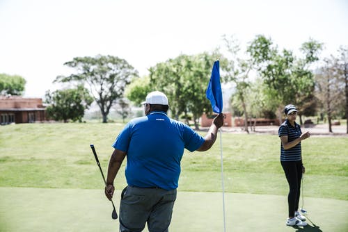 拿着蓝色小旗的人拿着高尔夫球司机 · 免费素材图片