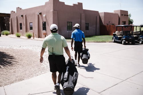 两名男子拿着高尔夫球袋 · 免费素材图片