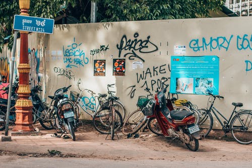 自行车和摩托车停在墙上涂鸦 · 免费素材图片