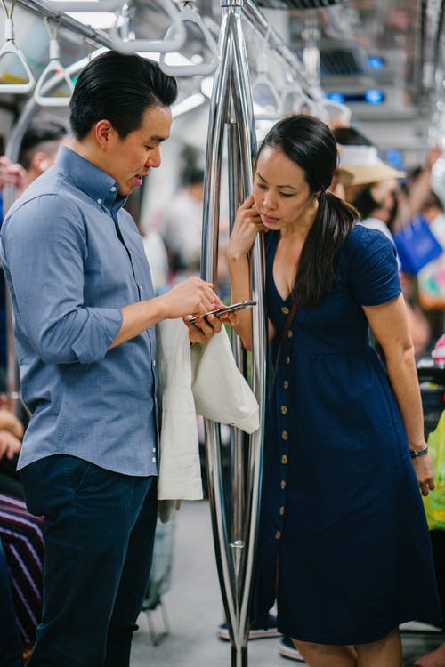 男人穿着蓝色按钮礼服衬衫拿着智能手机 · 免费素材图片