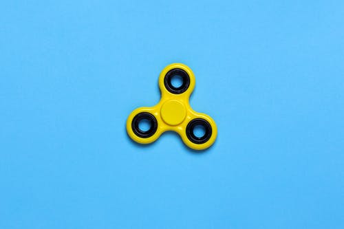 在蓝色桌面上的黄色三旋陀飞轮玩具 · 免费素材图片