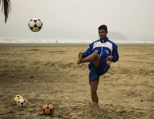 在海滩上踢足球的人 · 免费素材图片