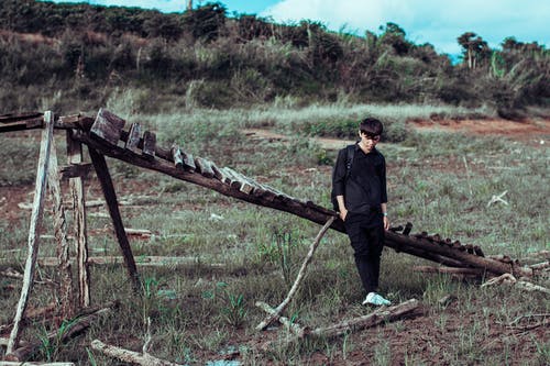 男子斜倚在草地上的木桥 · 免费素材图片
