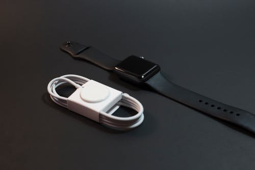黑色铝制表壳apple Watch，在磁力充电器旁边带有运动表带 · 免费素材图片