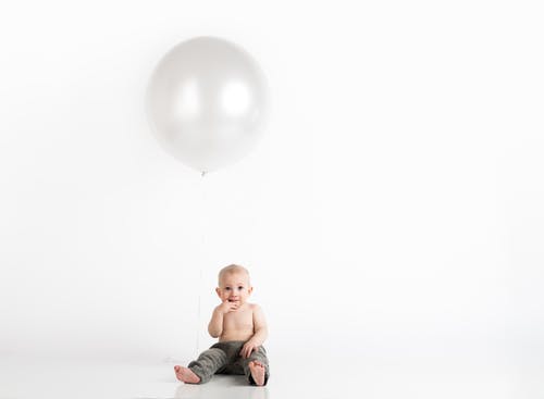 男婴坐在上面的白色充气气球 · 免费素材图片